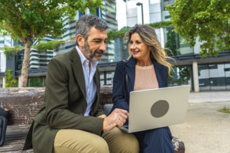 Mature business professionals, man and woman, discussing project ideas and networking on a park