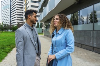 Diverse business professionals discussing work on a modern city street, representing teamwork,