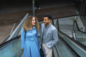 Two diverse business colleagues engaging in conversation while traveling on an escalator,