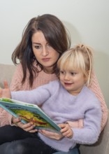 A mother reads a book together with her blonde girl, 4 years old, in Ystad, Skåne County, Sweden,