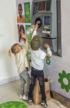 Two children, 5 and 7 years old, earn pocket money by recycling cans in a recycling machine in