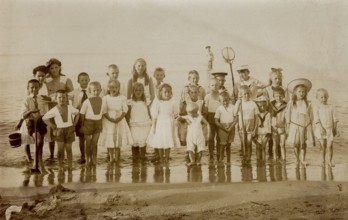 Digitally restored historical photograph of a large group of children on the Baltic Sea beach of