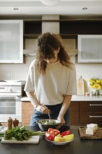 Woman mix grated goat cheese and chopped cilantro into a bowl in the kitchen