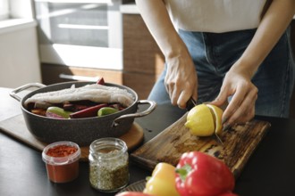 Hands of a woman using knife to cut a lemon in half on a chopping board