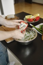 Female fingers pressing the cheese filling into bell pepper
