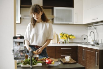 Joyful woman preparing healthy food in a modern kitchen and recording video recipe