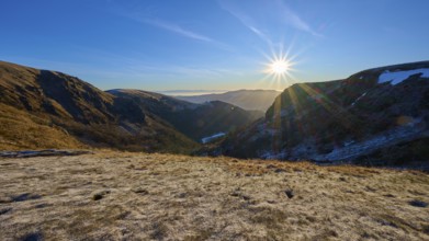 Frost-covered mountain landscape at sunrise with clear sky and bright sunlight, winter, Route de
