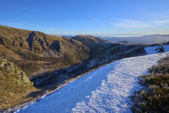 Snowy mountain slopes under blue sky revealing a vast valley and mountains, winter, Route de