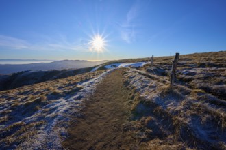 Path on a frosty mountain ridge in sunlight, with a wide view of peaceful nature, winter, Route de