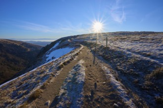 A sunny trail leads over a frosty mountain surrounded by clear air and blue skies, winter, Route de