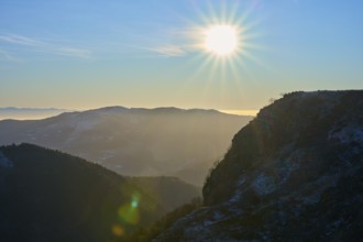 Sunrise behind mountains with bright sky and silhouette of a mountain ridge in a morning