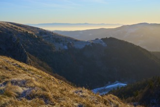 View of a snowy mountain range at sunrise with fog in the valley, morning, winter, Hohneck, La