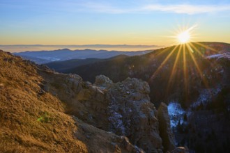 View of a rock formation illuminated by the low sun in the mountains, looking towards the Rhine