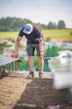 A worker on a construction site measures something while installing solar systems, new park and