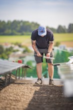 A man on a construction site measuring for the installation of solar systems, new Park and Ride