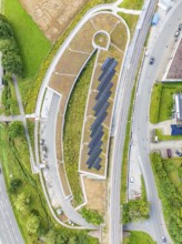 Aerial view of a building with solar panel, surrounded by roads and green vegetation, new park and