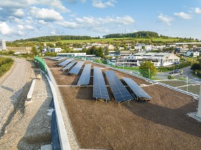 Solar systems on a flat roof with wide green areas and buildings in the background, new Park and
