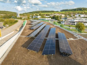 Solar module field in an urban environment with green landscape in the background, new park and