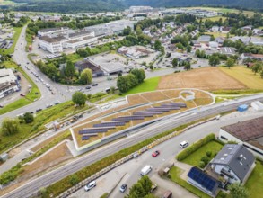 Aerial view of solar panels on a hill surrounded by urban infrastructure, new park and ride car