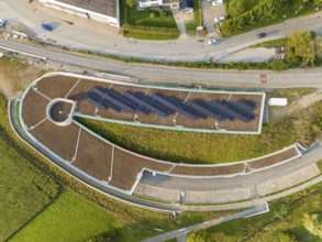 Aerial view of a solar cell field on a roof with surrounding roads, new Park and Ride parking
