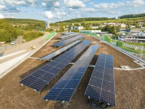 Arrangement of solar modules in a rural area with houses and hills, new park and ride parking