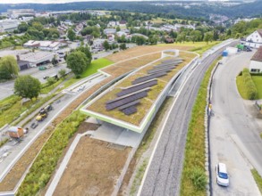 Aerial view of solar systems on a roof next to traffic routes and green spaces, new park and ride
