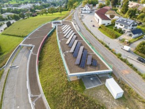 House roof with several solar panels surrounded by green landscape, new park and ride parking