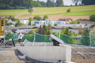 A worker on a construction site assembling solar panels in a rural area, new park and ride parking