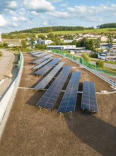 Solar panels on a hill roof with a view of rural surroundings and buildings, new park and ride