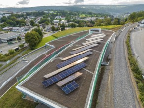 Expanded solar system on a roof with a view of a green landscape and city, new park and ride