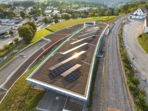 A roof with solar panels in a lively landscape with a view of a city, new park and ride parking
