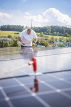 Worker checking solar modules in a landscaped area with clear skies, new park and ride Calw