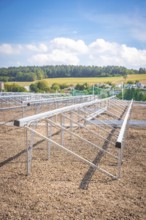 Metal structures for solar panels in an open field under a blue sky, new park and ride car park
