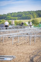 Several workers install solar panels on large racks in a scenic area, new Park and Ride Calw