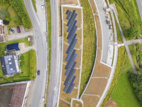 Aerial view of solar panels on a roof between roads in an urban area, new park and ride parking