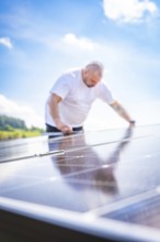 Man bends over a solar panel in a natural environment in bright light, new park and ride parking