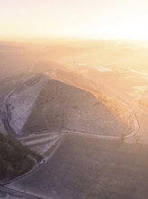 View of a snow-covered hill in fog and warm light, old deposit, construction site for PV open space