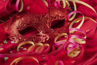 Red mask with confetti, feathers and colorful streamers, carnival