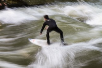 Surfers standing on Eisbach wave in the English Garden Munich, Upper Bavaria, Germany