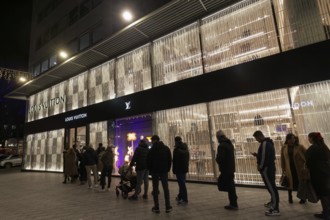 Queue in front of the Louis Vuitton boutique on the Kö, illuminated façade, evening, luxury