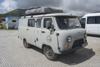Grey van in a parking lot on a cloudy day, UAZ-452, Buchanka, Georgian motorhome, camper, Georgia