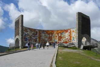 People look at a large wall painting on a curved stone wall, Georgian-Russian Friendship Memorial,