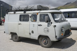 Grey van with roof rack in the background of mountains, atmospheric and adventurous, UAZ-452,