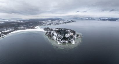 The wintry and snowy Mainau island in Lake Constance with the pier and the baroque Mainau Castle,