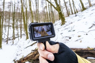Hand holding an action camera showcasing a person recording a wide angle selfie video, creating