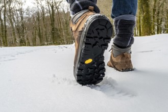 Hiker stepping in deep snow with rugged sole hiking boots, showcasing outdoor trekking, adventure,