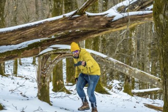 Man documenting outdoor adventure in a snow covered forest, holding a camera and filming himself