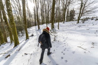 Woman walking along a snow covered path, leaving footprints in the fresh snow while exploring a