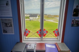 Window with Norwegian flags in the room, view of outdoor scene and books in the partisan museum in