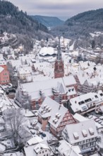 Snowy old town district with church and half-timbered houses in a mountain backdrop, Calw, Black